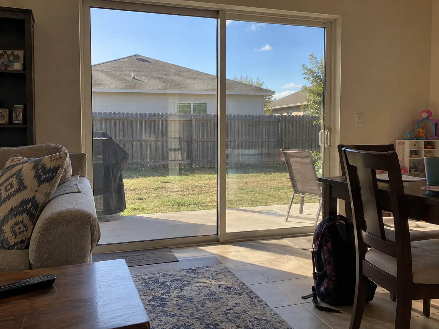 Sliding glass doors beside a lived-in family room with a bag and shoes near the entry.